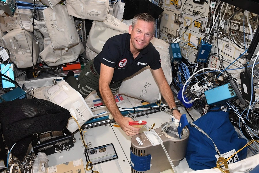 male astronaut cooking chocolate mousse inside ISS using small equipment